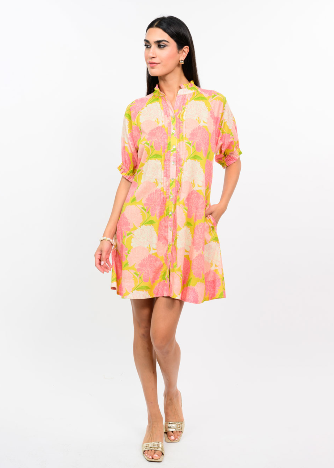 Woman wearing a pink and coral floral dress against a white background