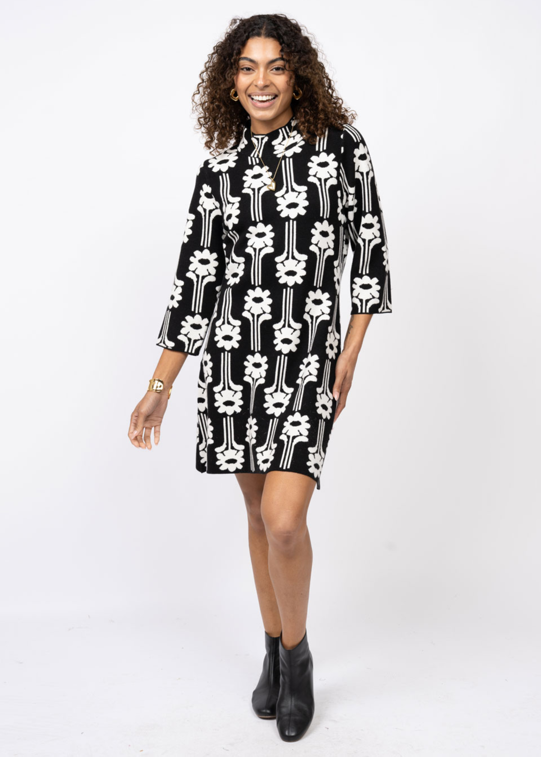 Woman wearing a black dress with a white pattern and 3/4 length sleeves in front of a white background