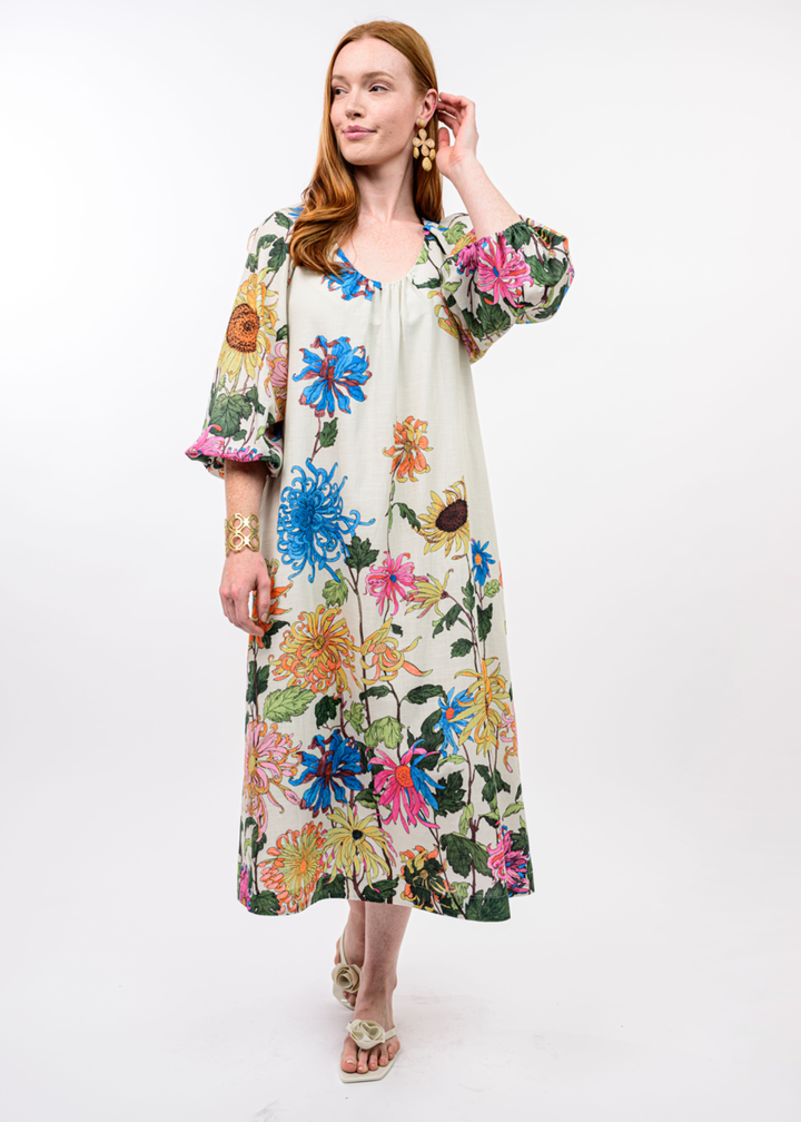 Woman wearing an ivory midi dress with a bright floral print