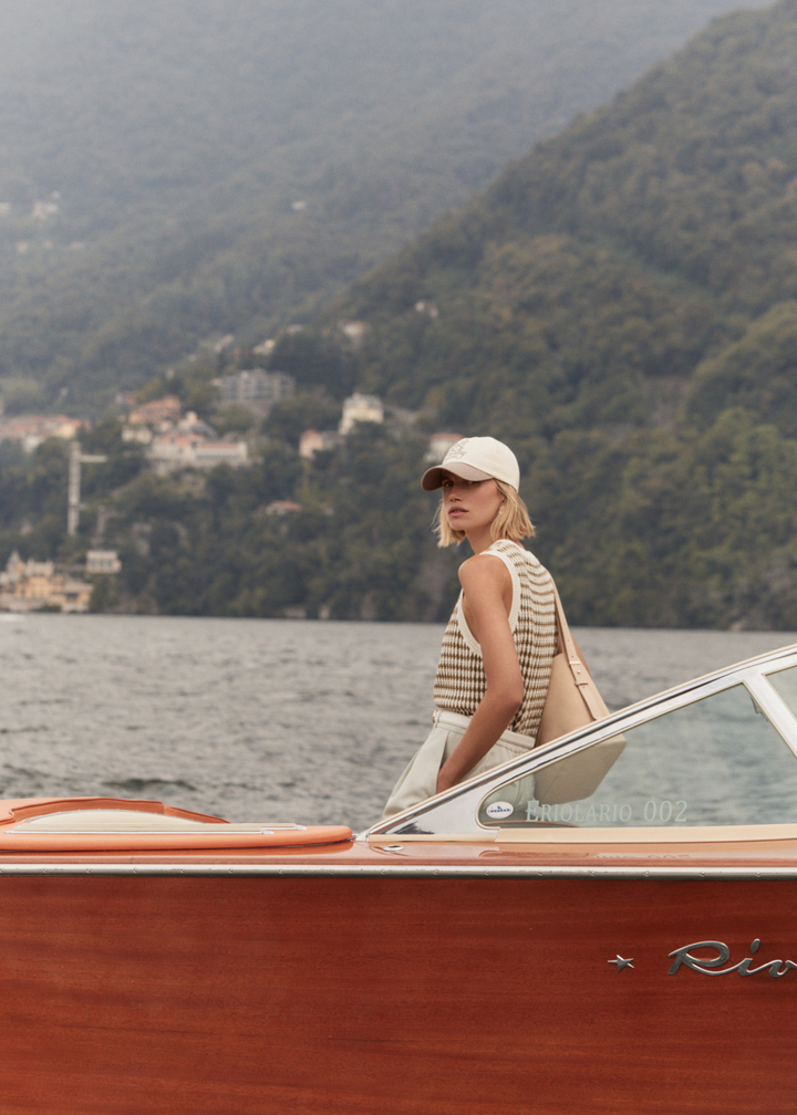 Woman on a boat wearing a brown and white knit button up tank top with white shorts