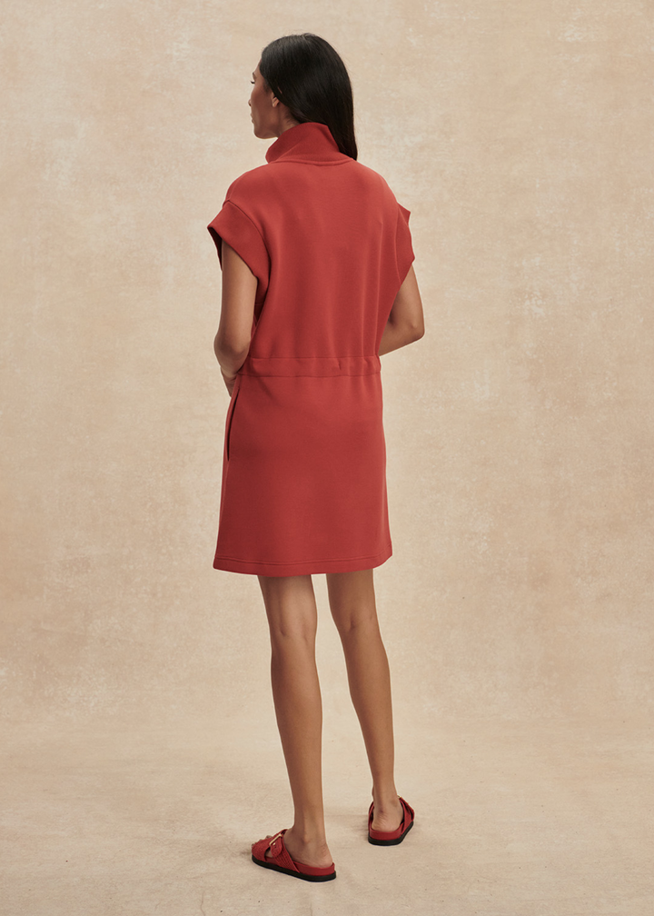 Woman turned around wearing a red/orange half zip mini dress