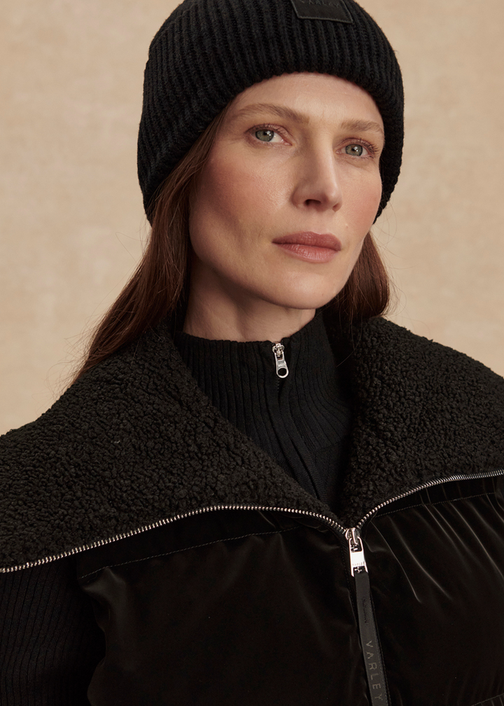 Close up of a woman wearing a black puffer vest with a sherpa neck