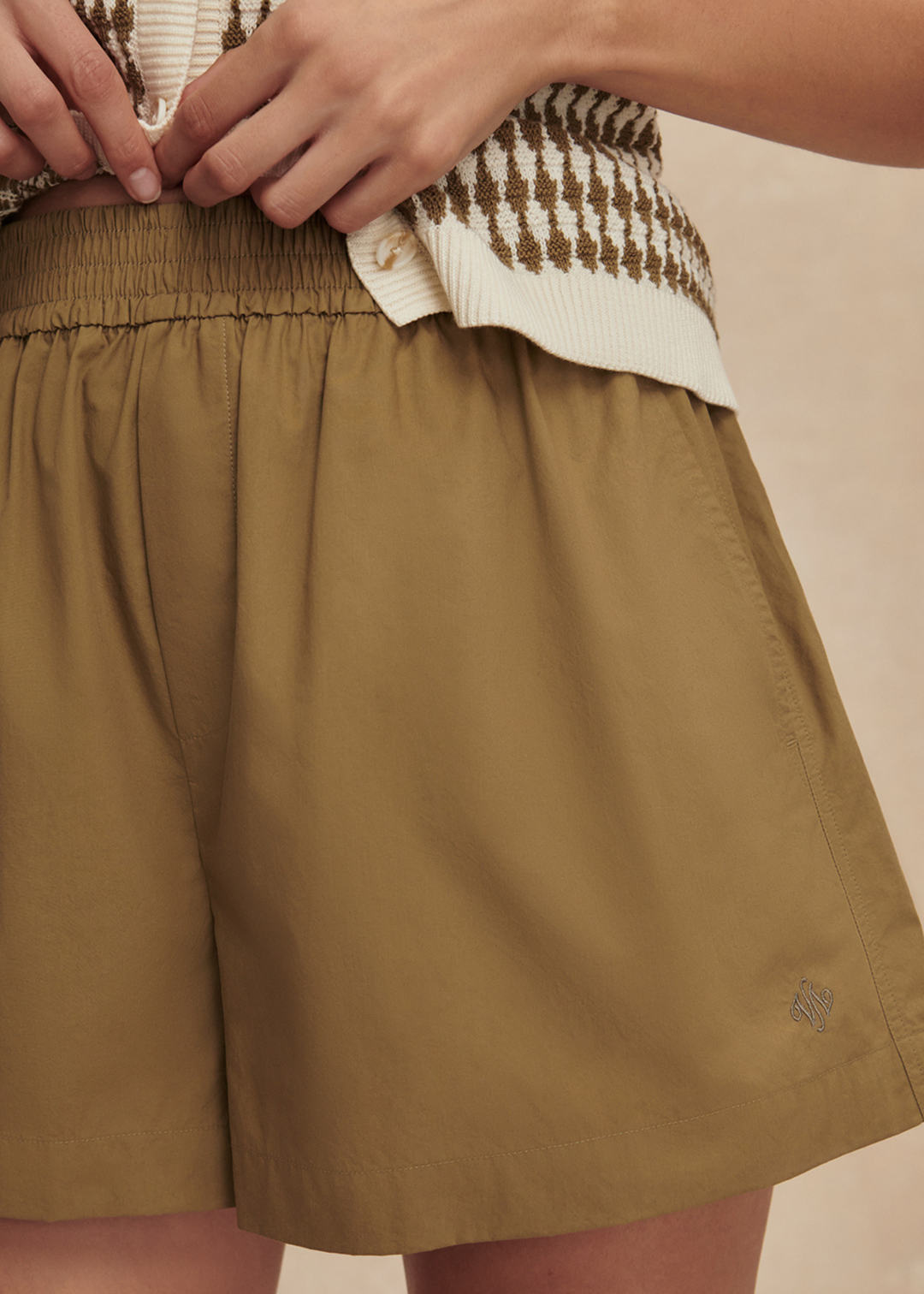 Woman wearing a gold and white knit tank with matching gold shorts