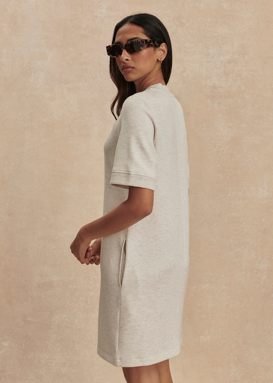 Woman turned to the side wearing an ivory half zip mini dress