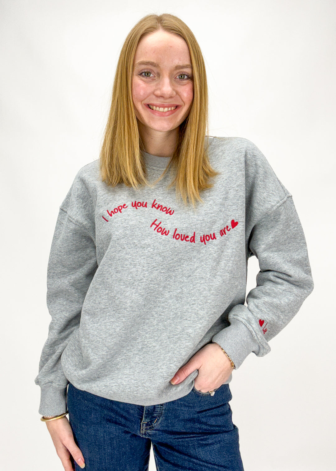 Person wearing a gray sweatshirt with red text on a white background