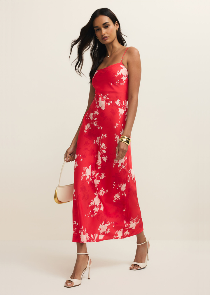 Woman wearing a red and white floral maxi dress against a white background