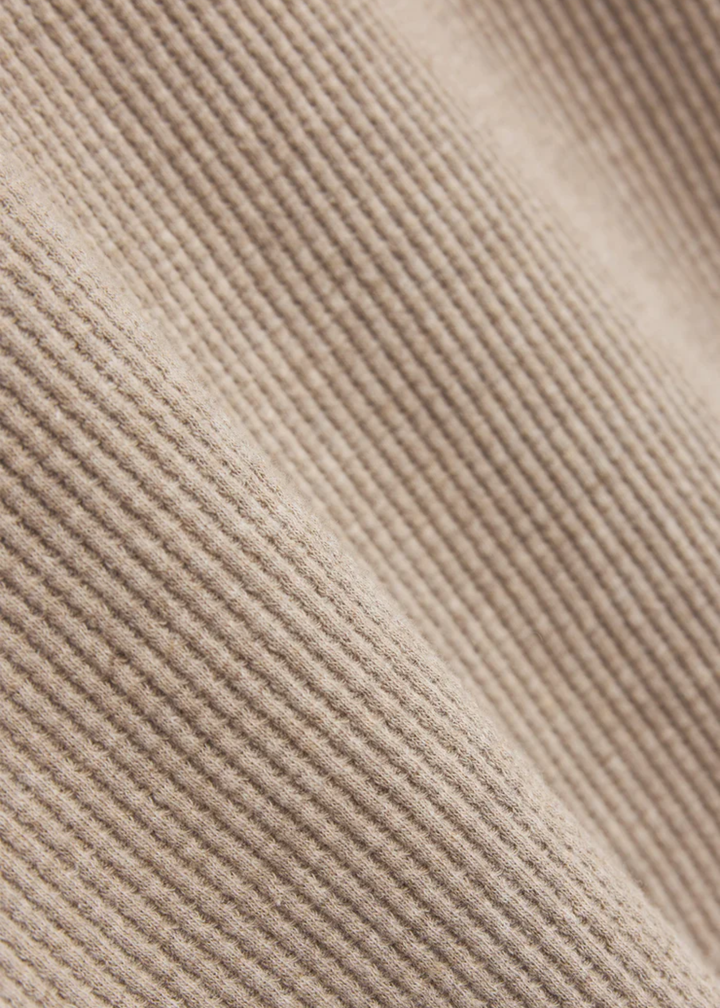 Close up of a beige top with a waffle knit texture