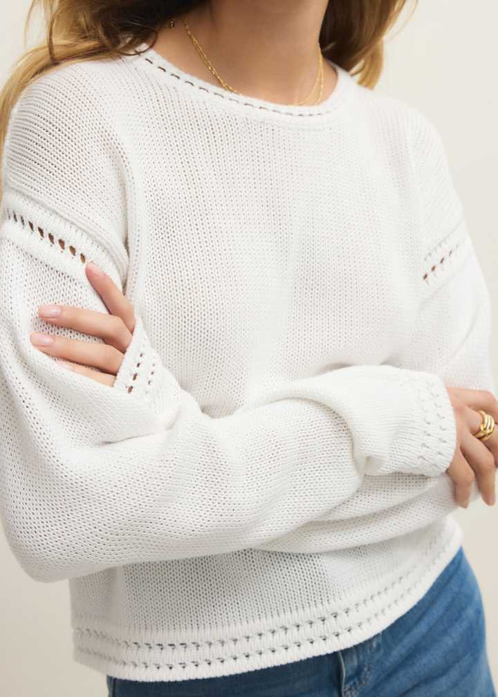 Close up of a woman wearing a white sweater with jeans