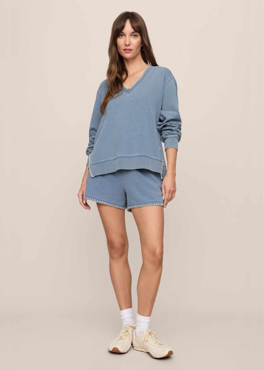Woman wearing a blue knit denim sweatshirt with whipstitch trim and matching shorts