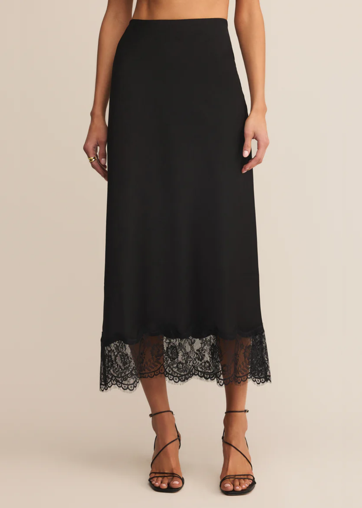 Woman wearing a black satin skirt with a lace trim and black heels