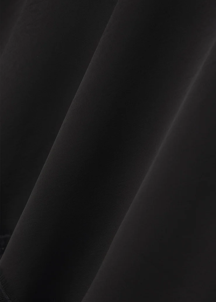 Close up of the material of a black satin skirt