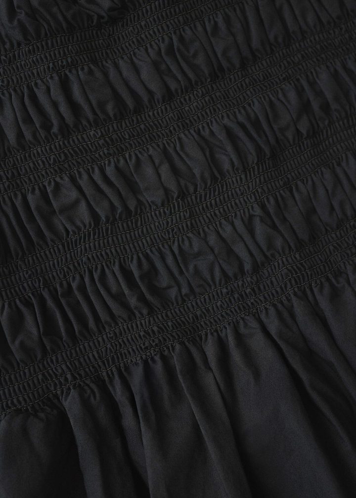 Close up of a black dress with ruched fabric