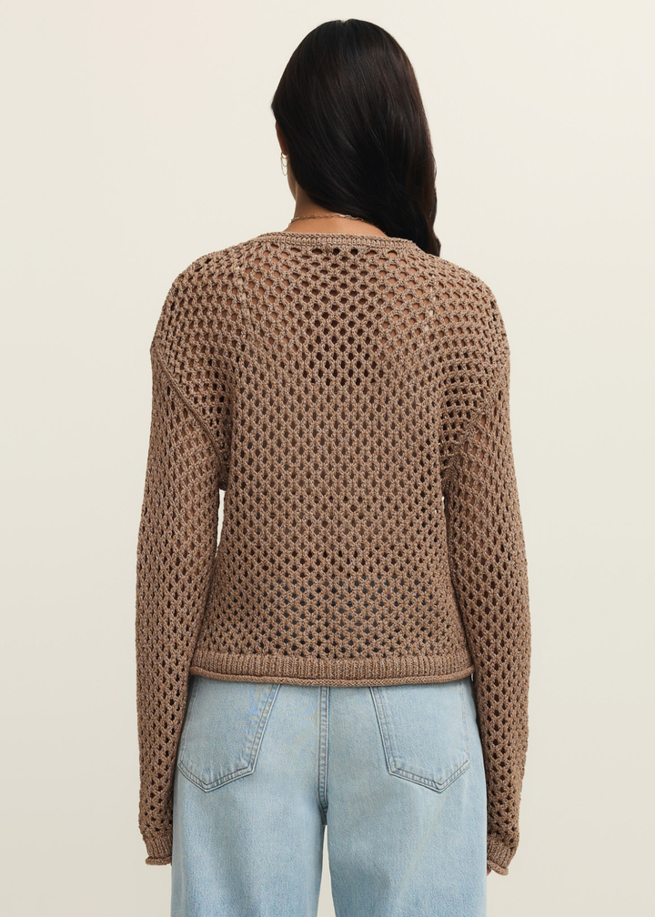 Woman turned around wearing a brown shimmer sweater with jeans