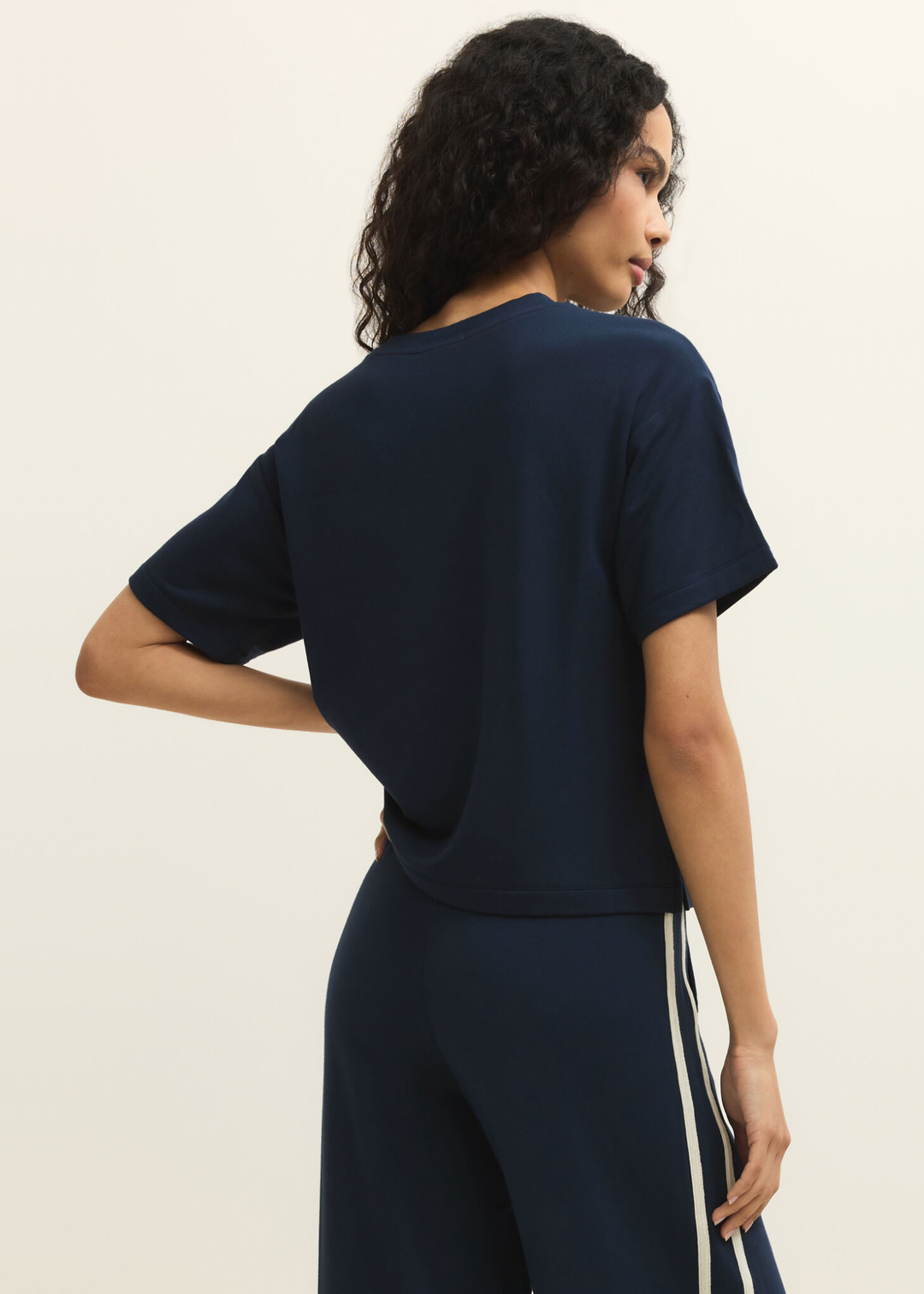 Woman turned around wearing a navy short sleeve tee with navy pants