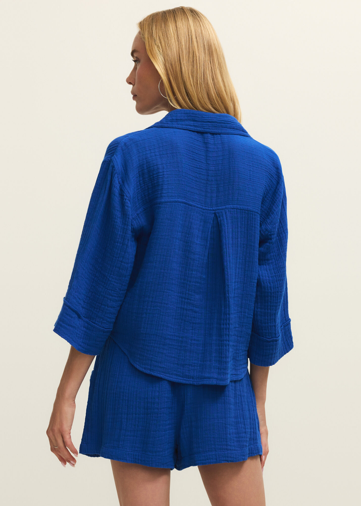 Woman turned around wearing a blue button down with matching shorts