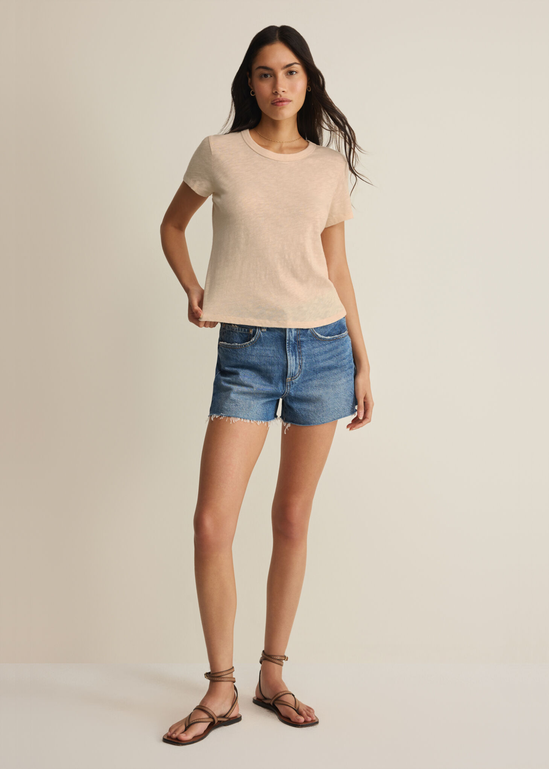 Woman wearing a tan t-shirt with denim shorts