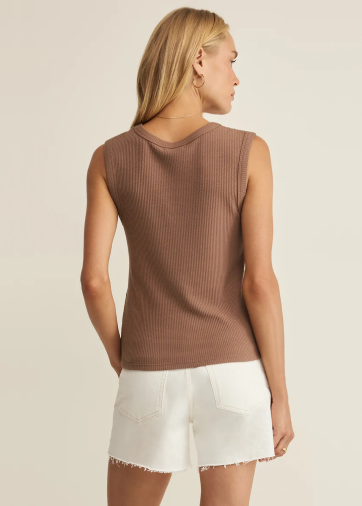 Woman turned around wearing a brown scoop neck tank top with white denim shorts