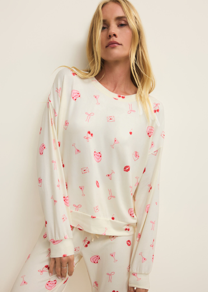 Woman wearing a white pj set with a pink and red graphic pattern