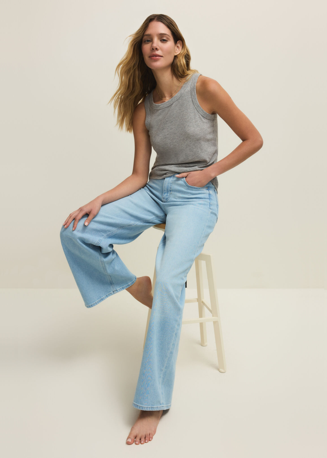 Woman wearing a grey tank top with jeans