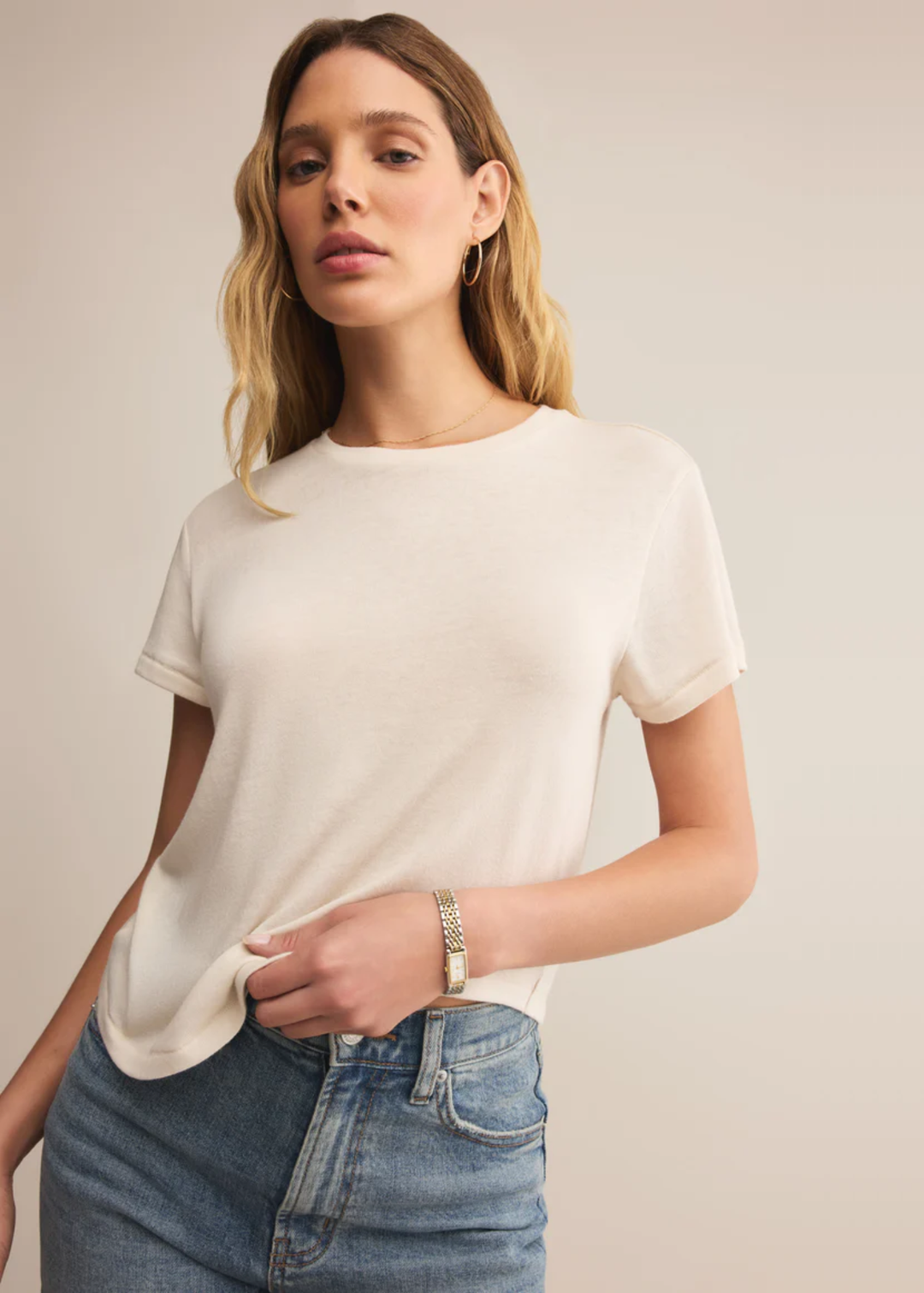 Woman wearing a white short sleeve shirt with jeans standing in front of a white background