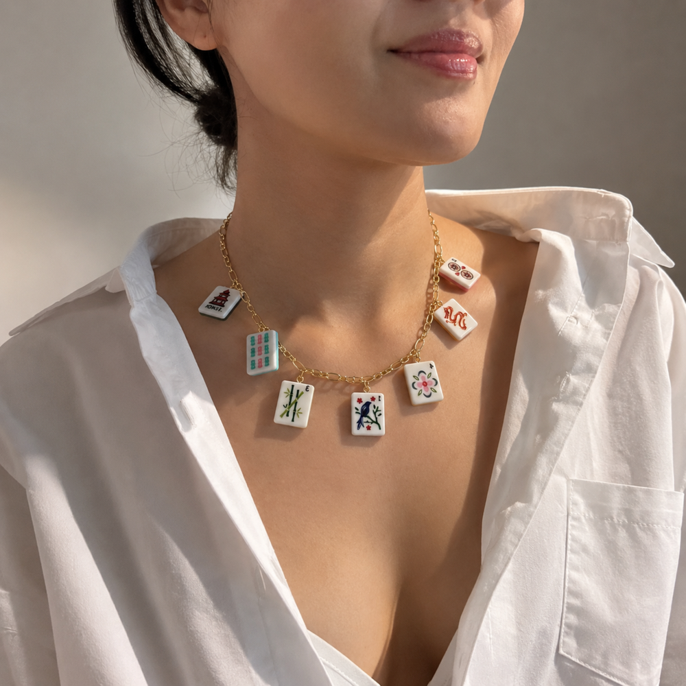 Necklace with card-themed pendants worn by a person in a white shirt.