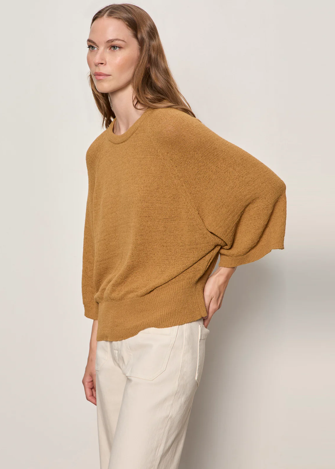 Woman wearing rust sweater with 3/4 length sleeves. 