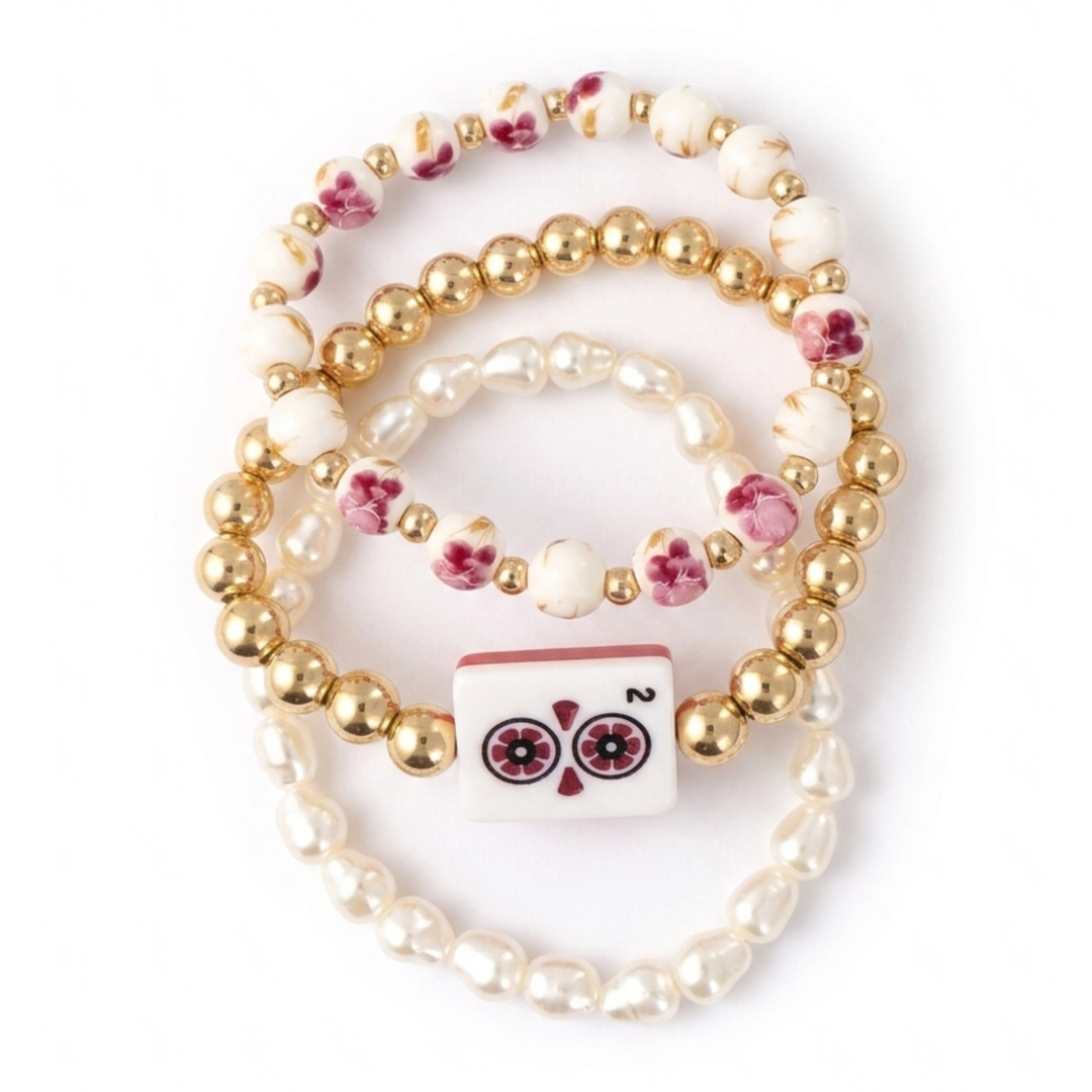 Bracelet with gold beads, white pearls, and a decorative owl charm on a white background