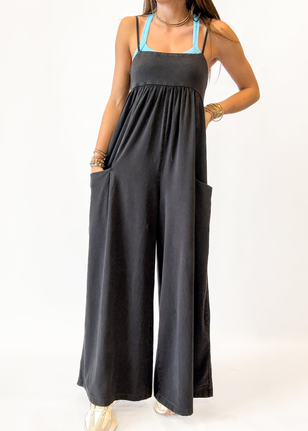 Woman wearing a black jumpsuit with a blue top on a white background