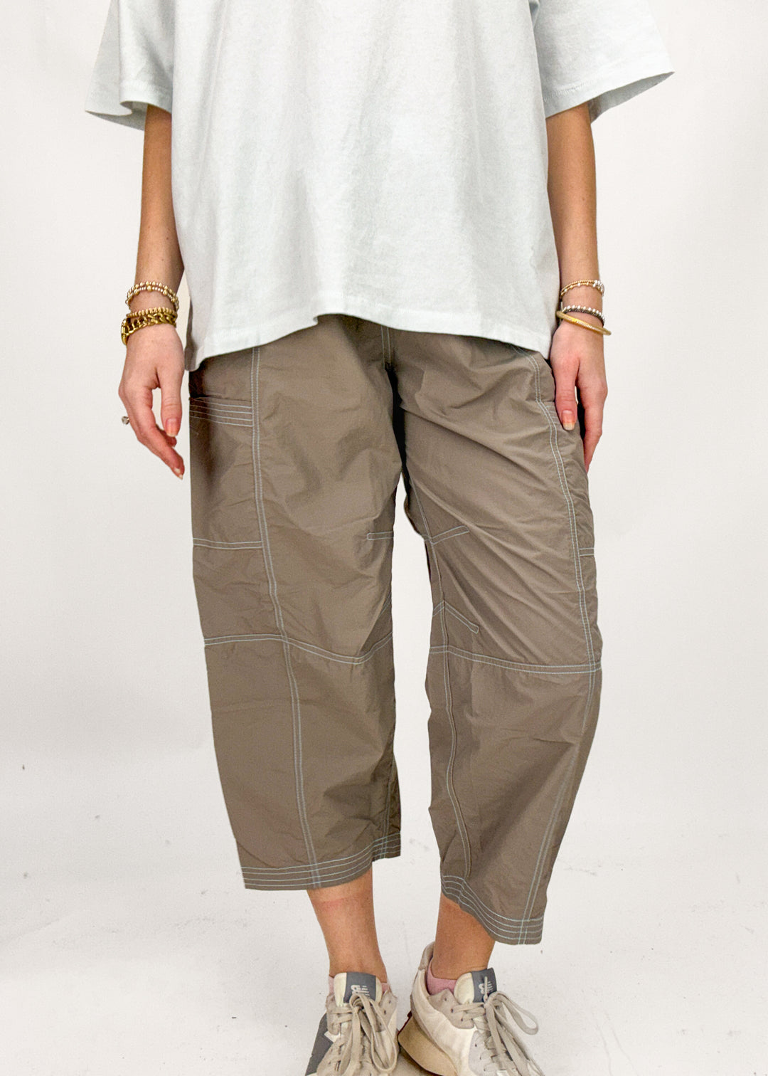 Person wearing a white oversized shirt and brown capri pants on a white background