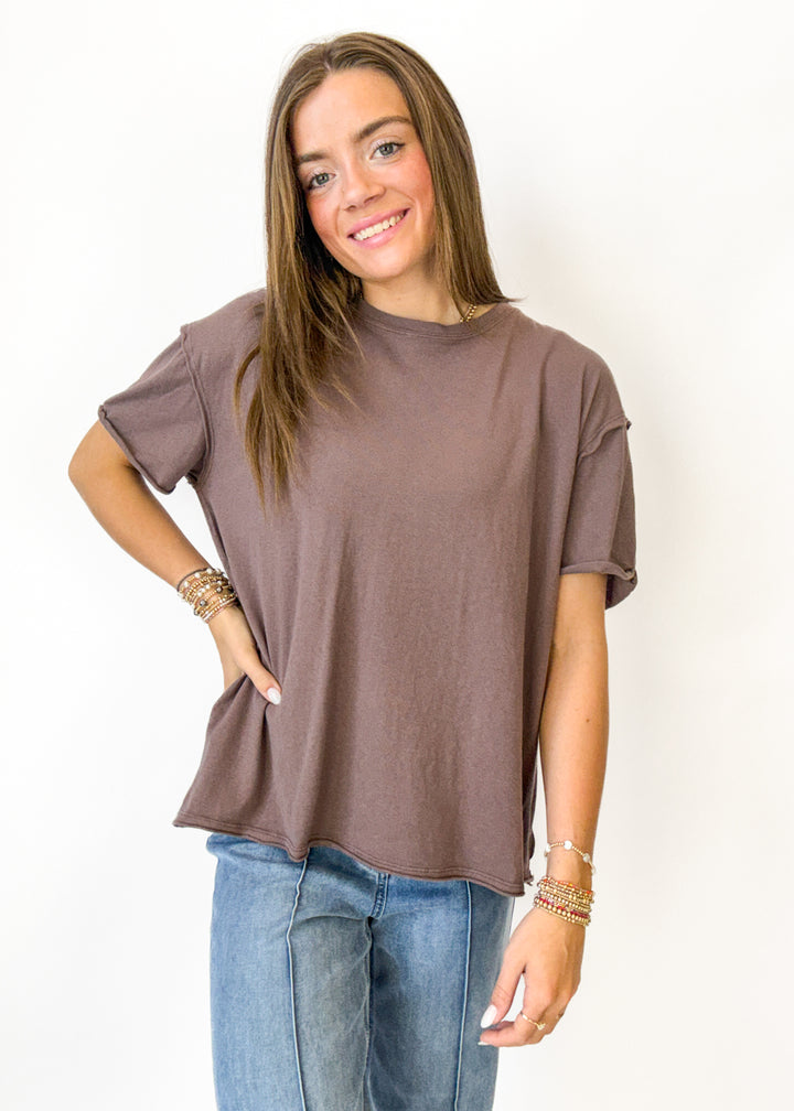 Woman wearing a brown t-shirt and blue jeans on a white background