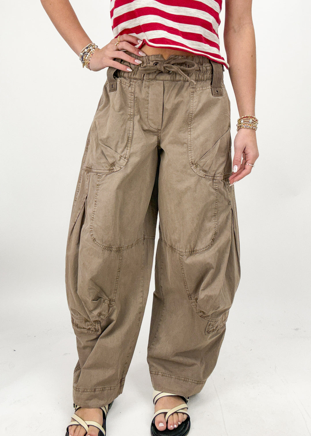Person wearing beige cargo pants and a red and white striped shirt on a white background