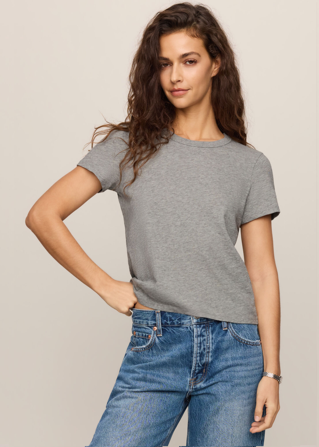 Woman wearing grey tee with her hand on her hip.