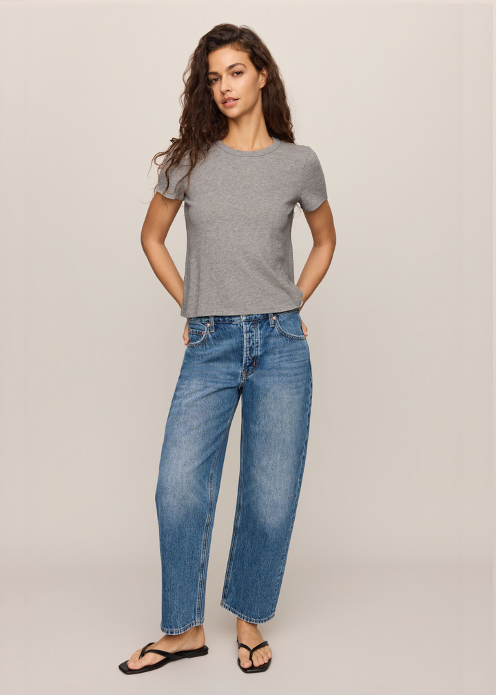 woman wearing grey tee with hands in her back pockets. 