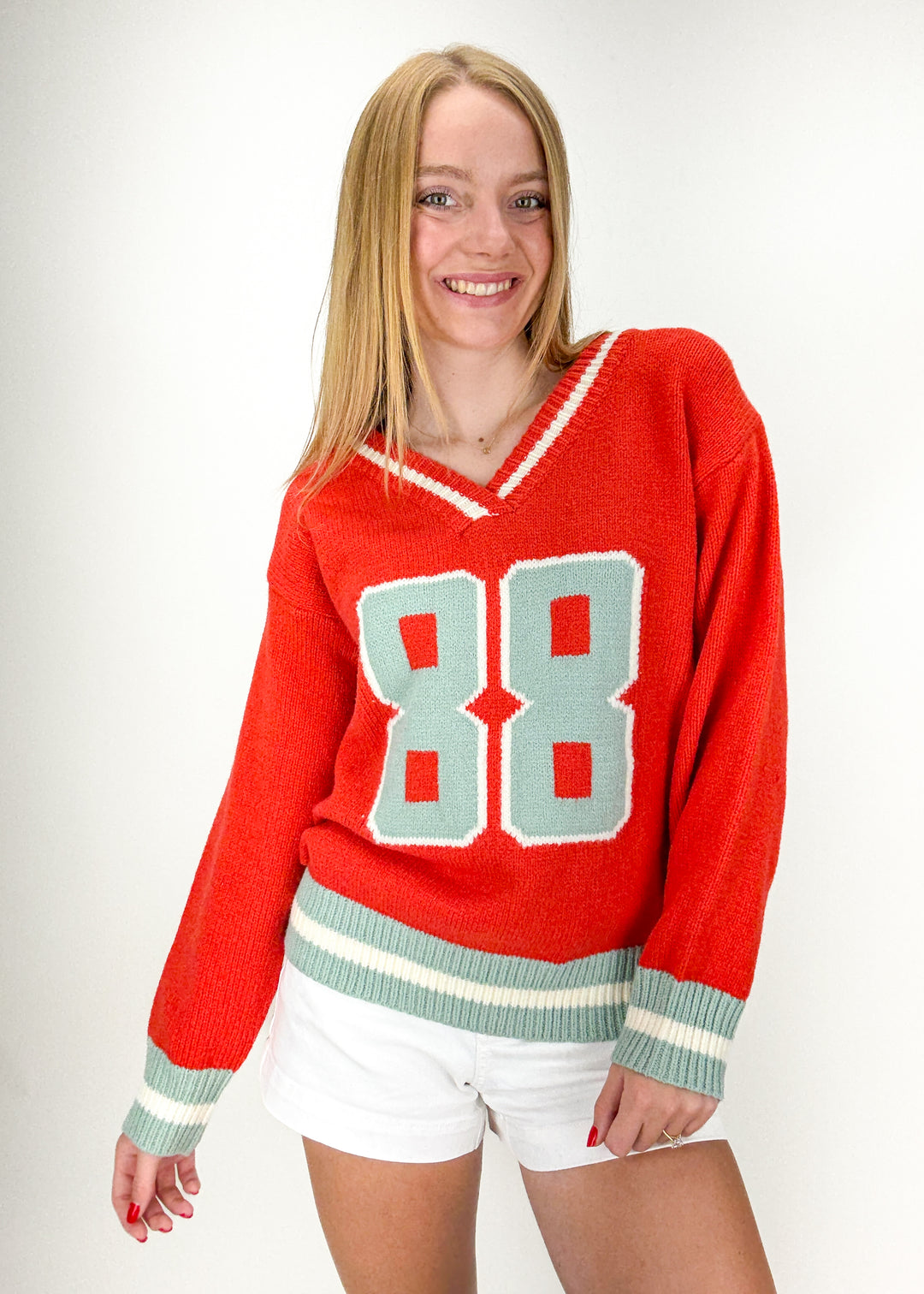woman wearing red and mint v-neck sweater with "88" jersey chest graphic