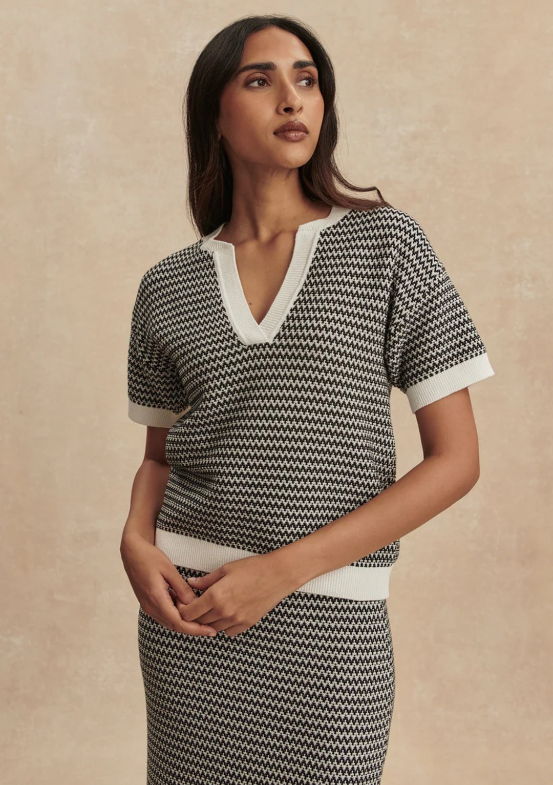 Woman wearing a black and white patterned dress against a beige background