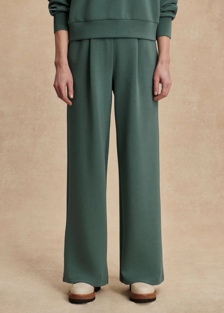 Person wearing a green outfit with wide-leg pants on a beige background