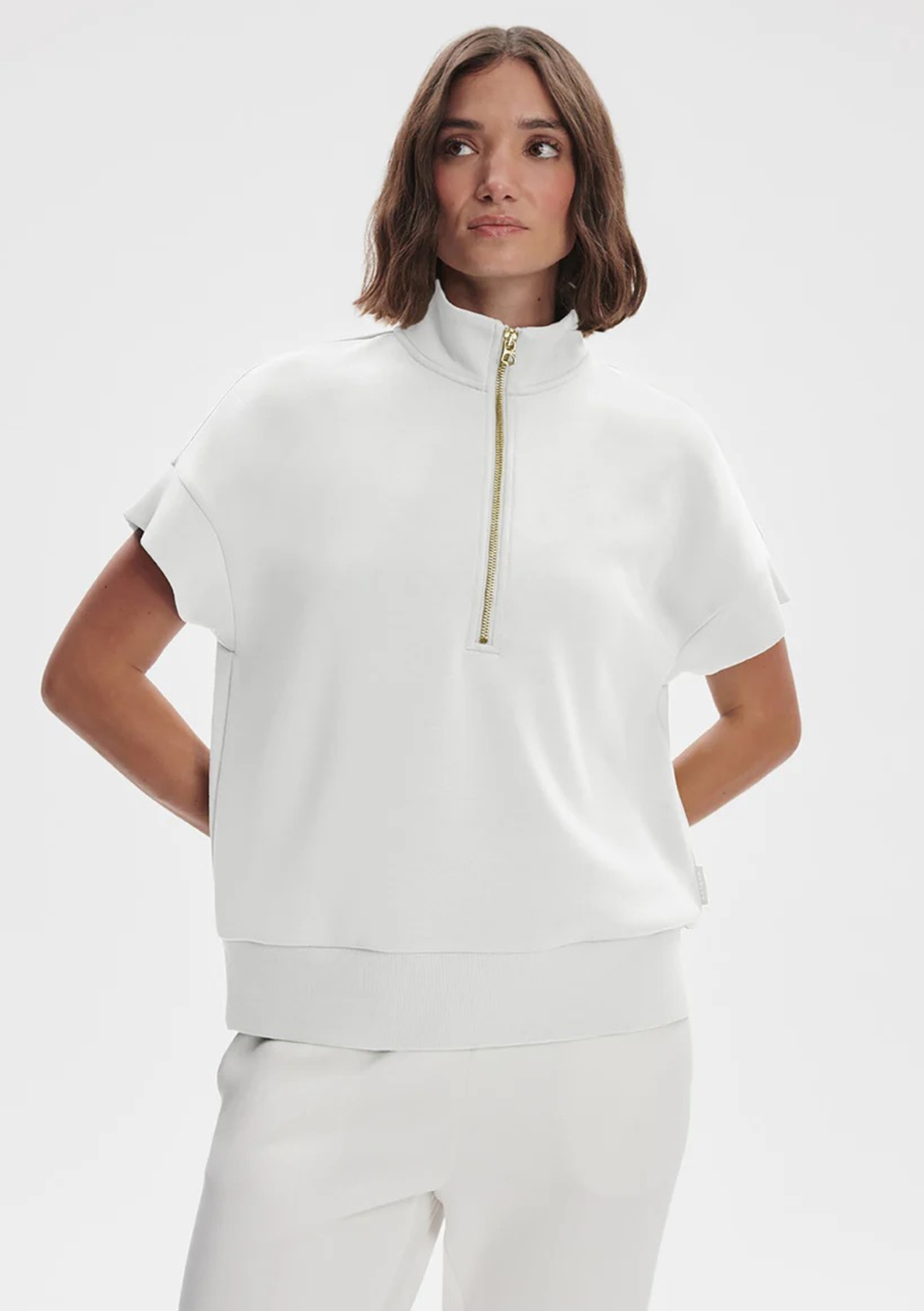 Woman wearing a white zip-up top on a light gray background