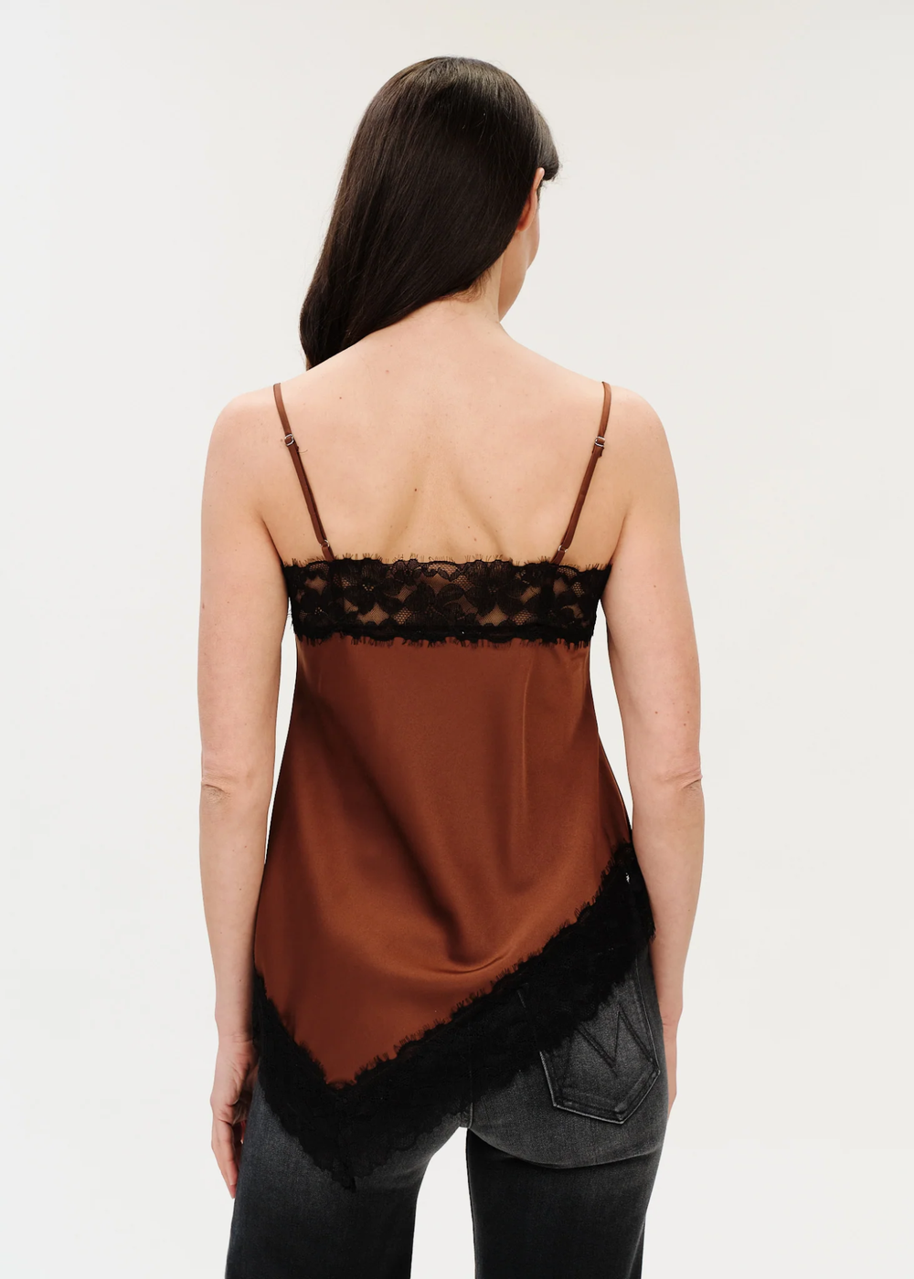 Woman wearing a spaghetti strap tank that is brown with black lace trim turned to the side.