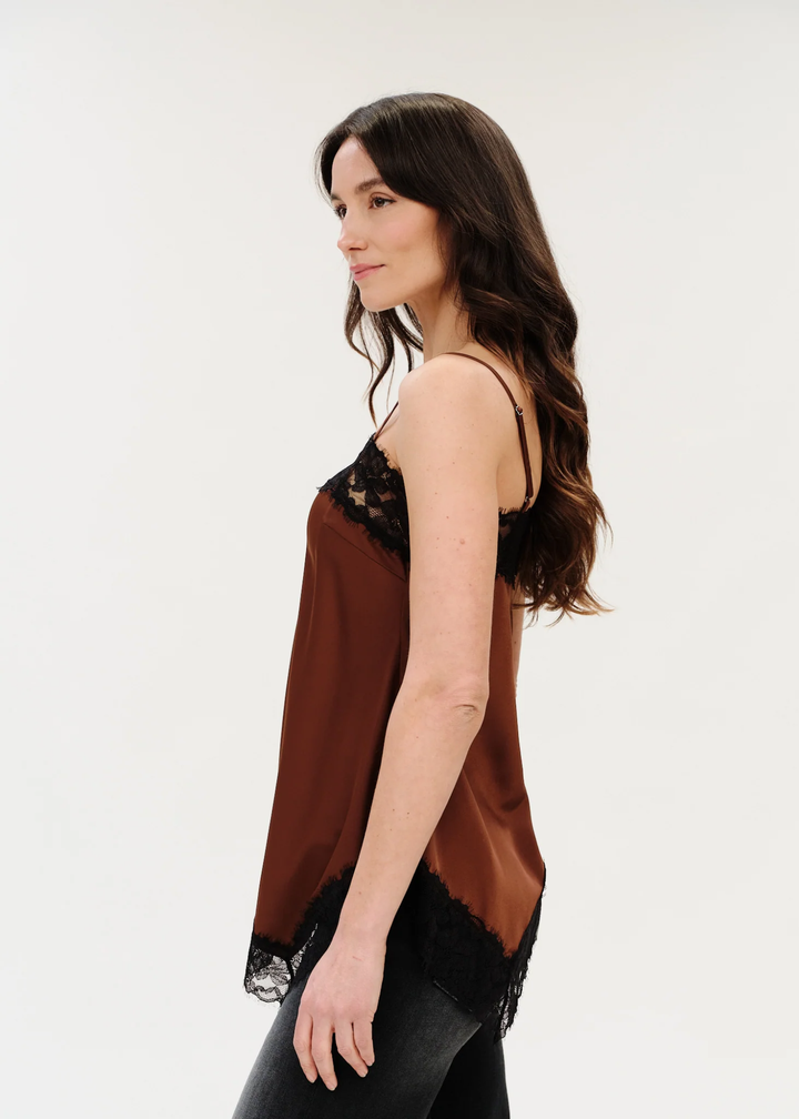Woman wearing a spaghetti strap tank that is brown with black lace trim turned to the side.