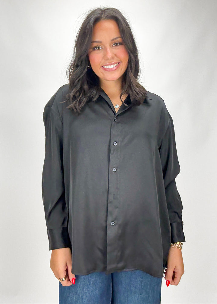 Woman wearing a black button-up shirt and blue jeans on a white background