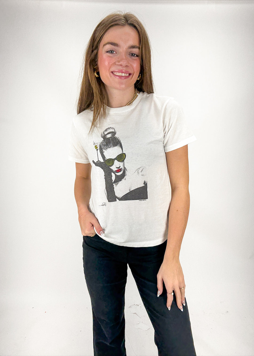 Person wearing a white t-shirt with a graphic design on a plain background