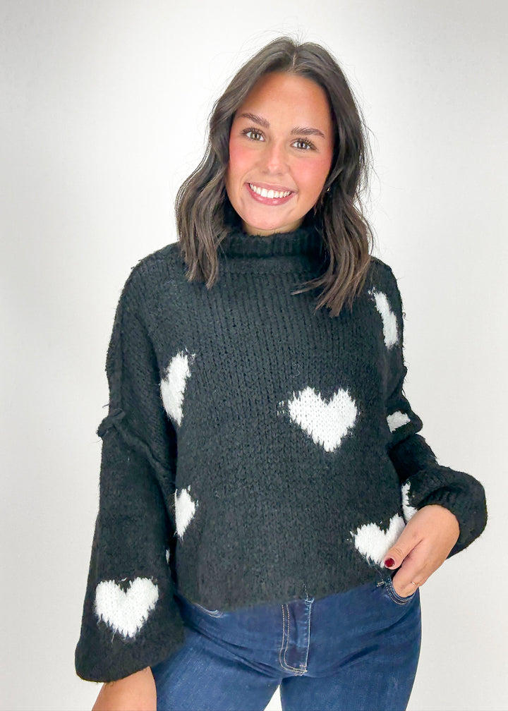 Woman wearing a dark gray sweater with white heart patterns 