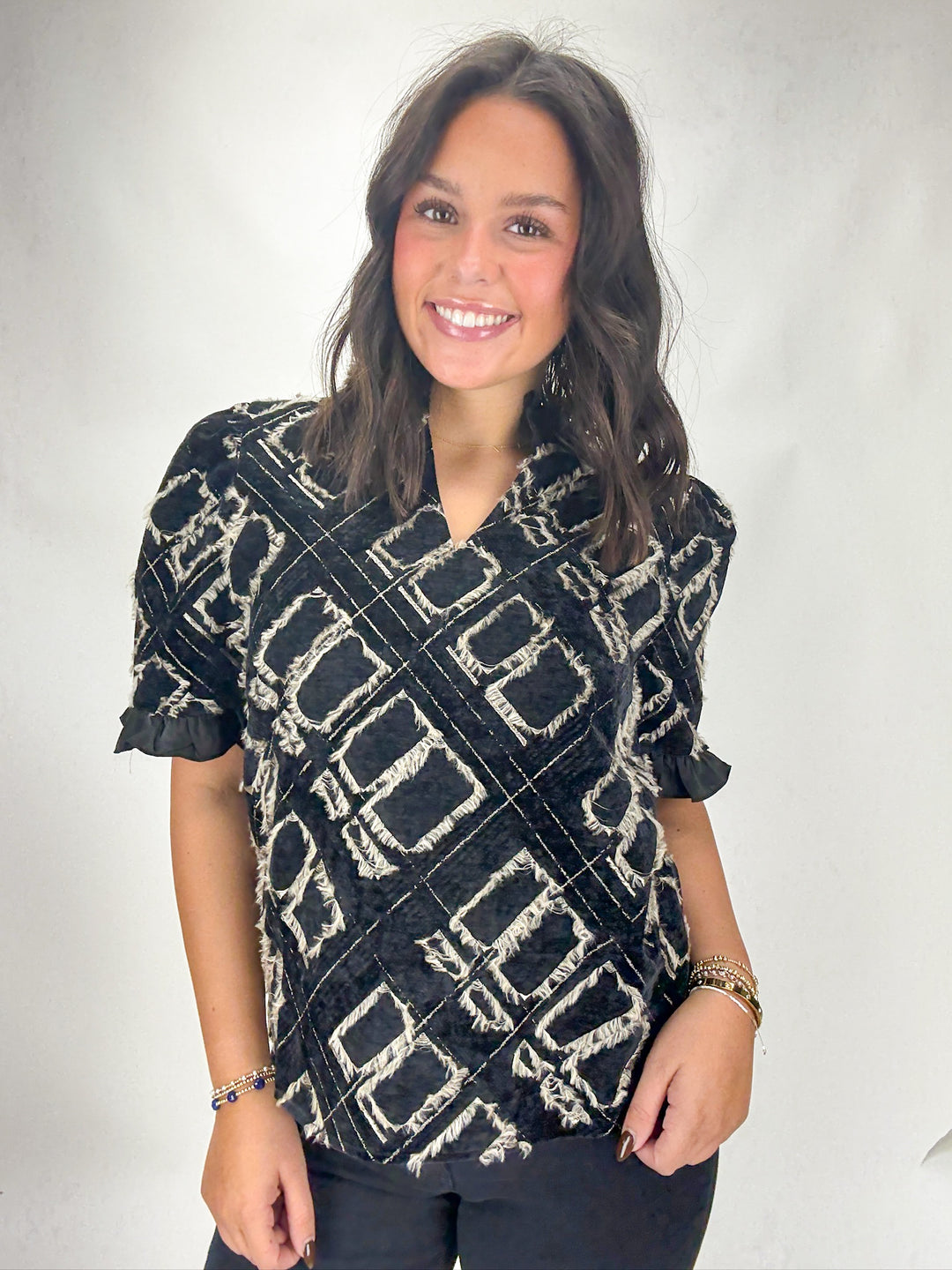 Woman wearing a black and white patterned top against a plain background