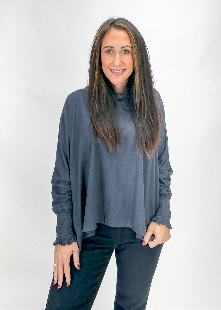 Woman wearing a gray long-sleeve top and black pants 