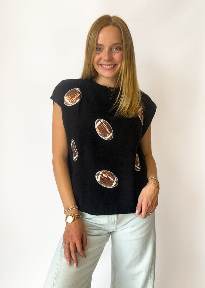 Woman wearing a black sleeveless top with football patches on a white background