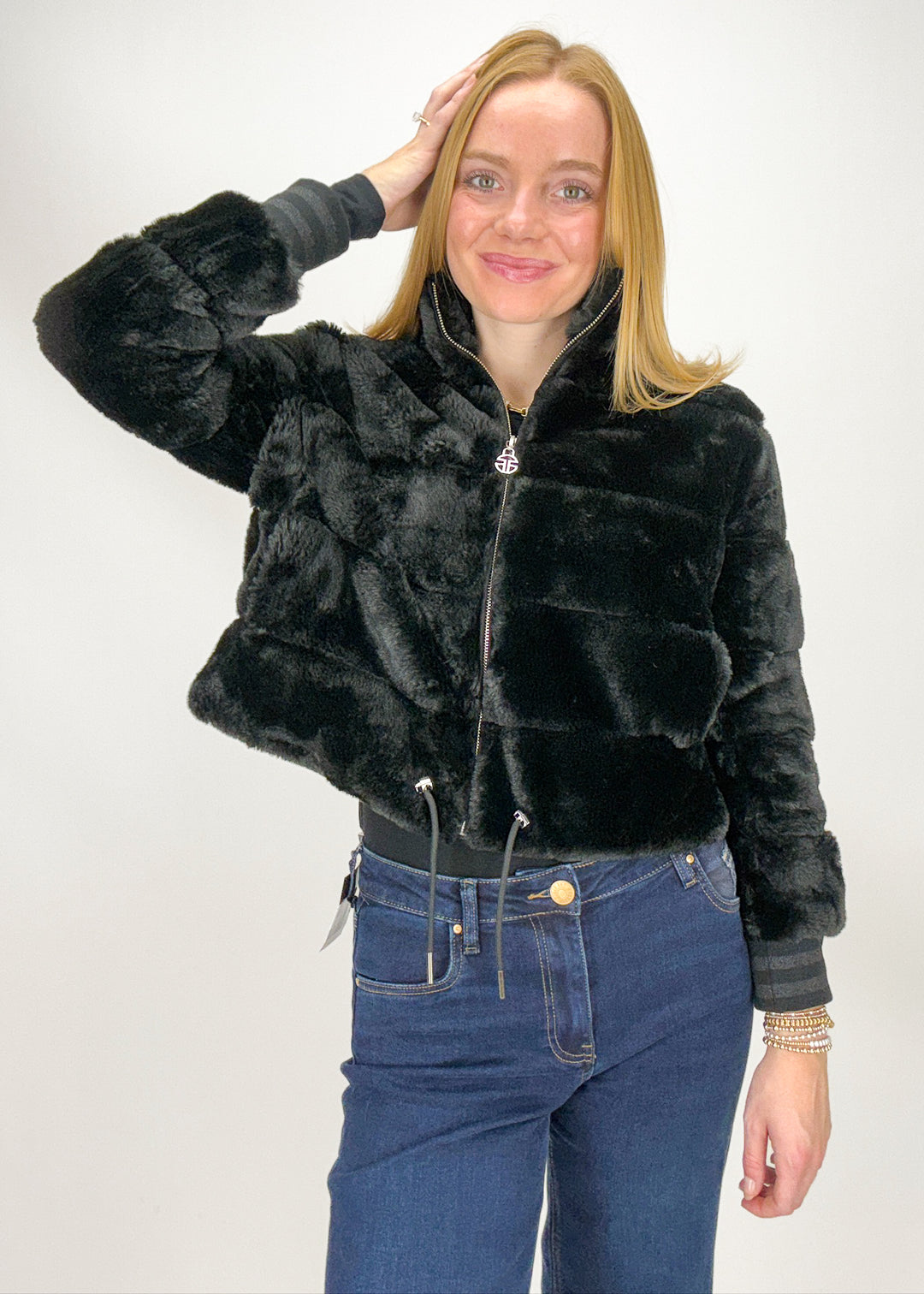 Woman wearing a black faux fur jacket and blue jeans 