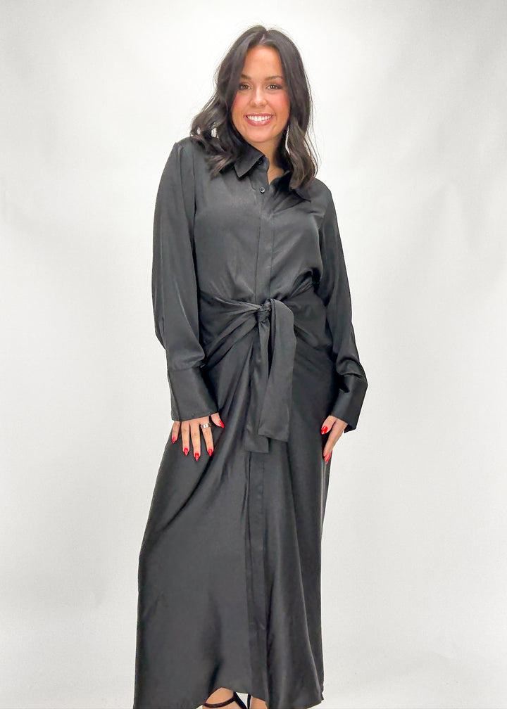Woman wearing a long black shirt dress against a white background