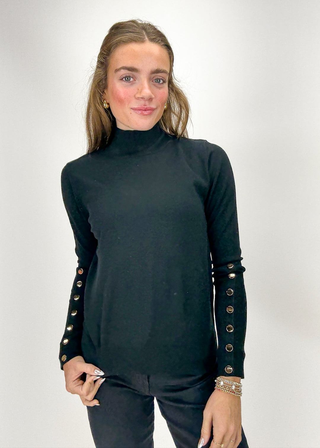 Woman wearing a black turtleneck with studded details