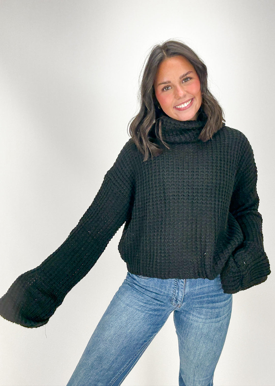 Woman wearing a dark green sweater and blue jeans 