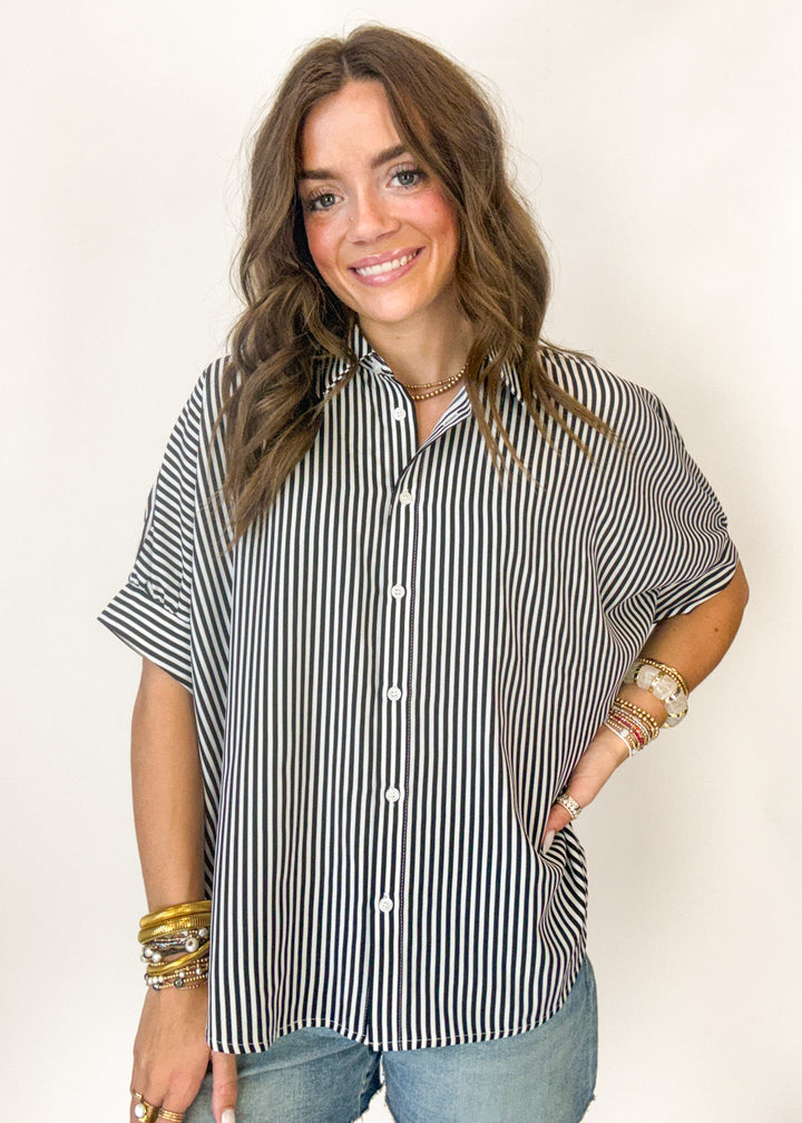 Woman wearing a black and white striped shirt with a plain background